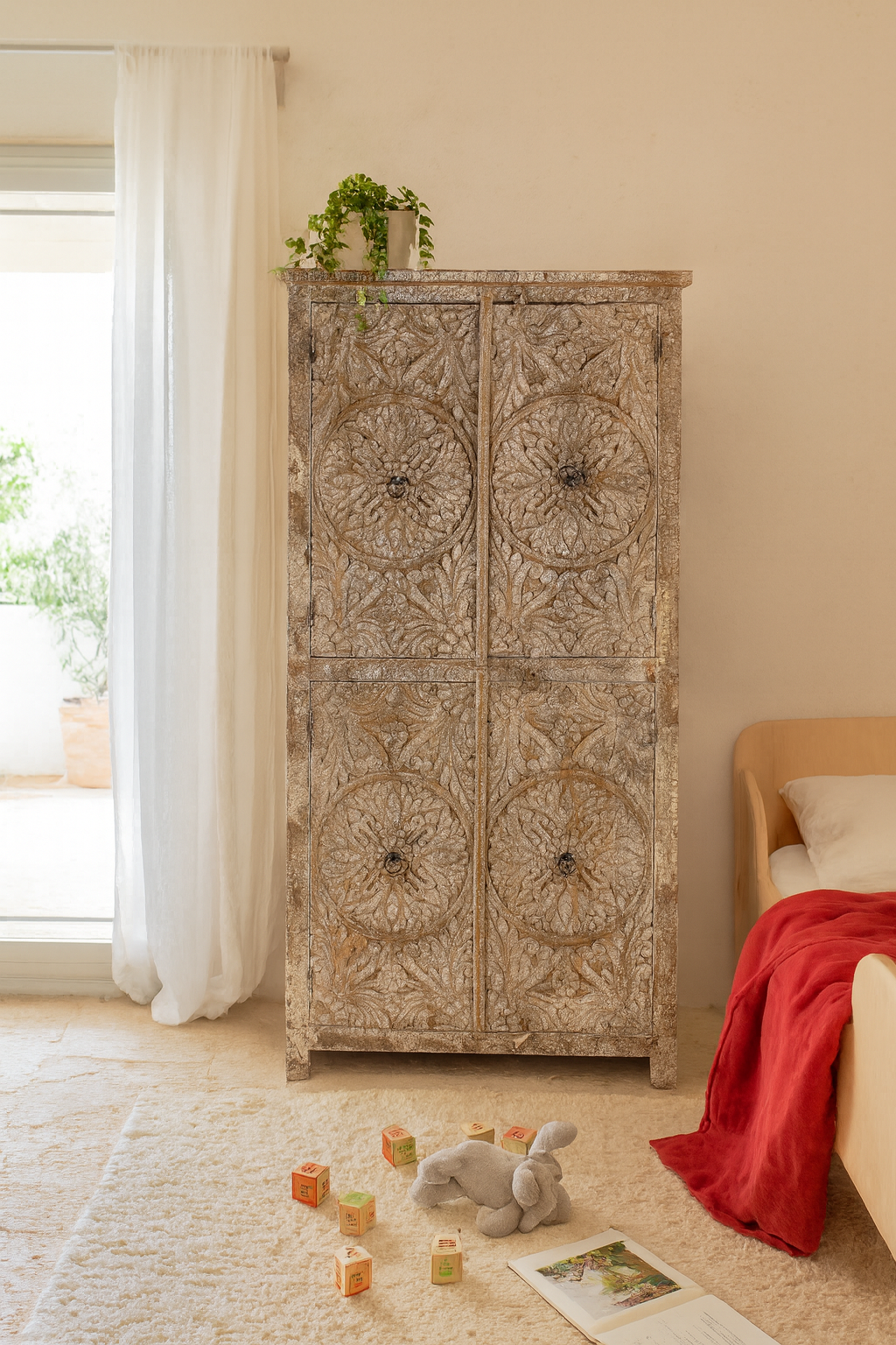 Lifestyle image of a hand-carved acacia wood wardrobe with floral detailing and distressed finish – vintage living room furniture with artisan craftsmanship.