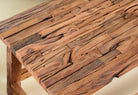 Close up image of a rustic-style coffee table made from driftwood, showcasing a textured, uneven surface with natural wood tones and grain variations, supported by a sturdy, simple wooden frame, styled in a cozy minimal setting with neutral decor.
