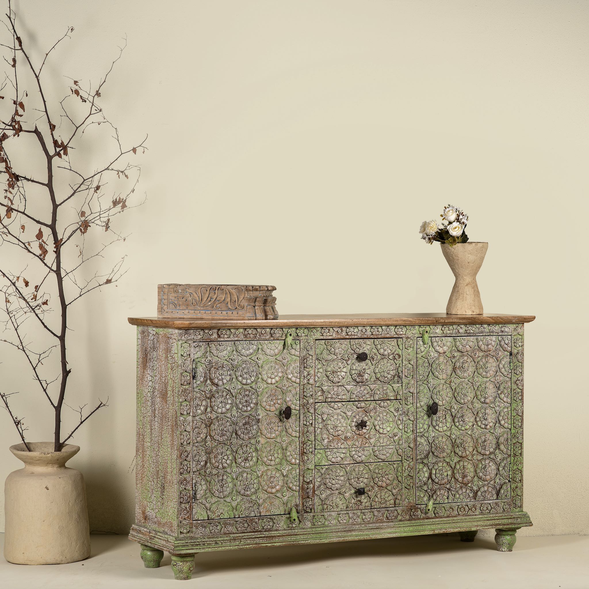 Side angle image of a carved wooden furniture sideboard with floral hand-carving and distressed finish, vintage style cabinet made from mango wood, 150 × 40 × 90 cm.