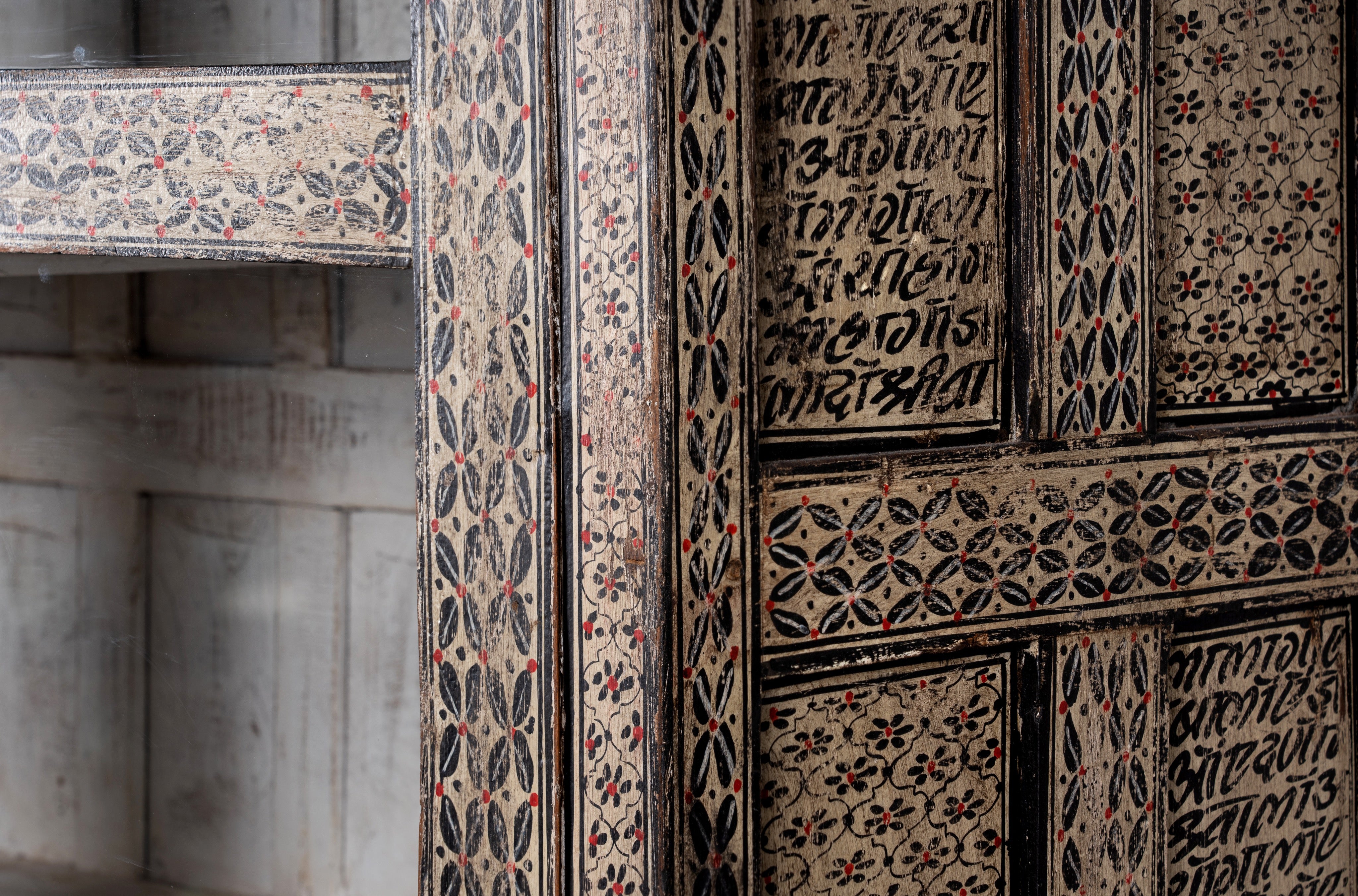 Close up image of a handcrafted display cabinet made from reclaimed Teak wood with glass doors and Sanskrit motifs; sustainable and unique wooden furniture, 182 × 93 × 42 cm.