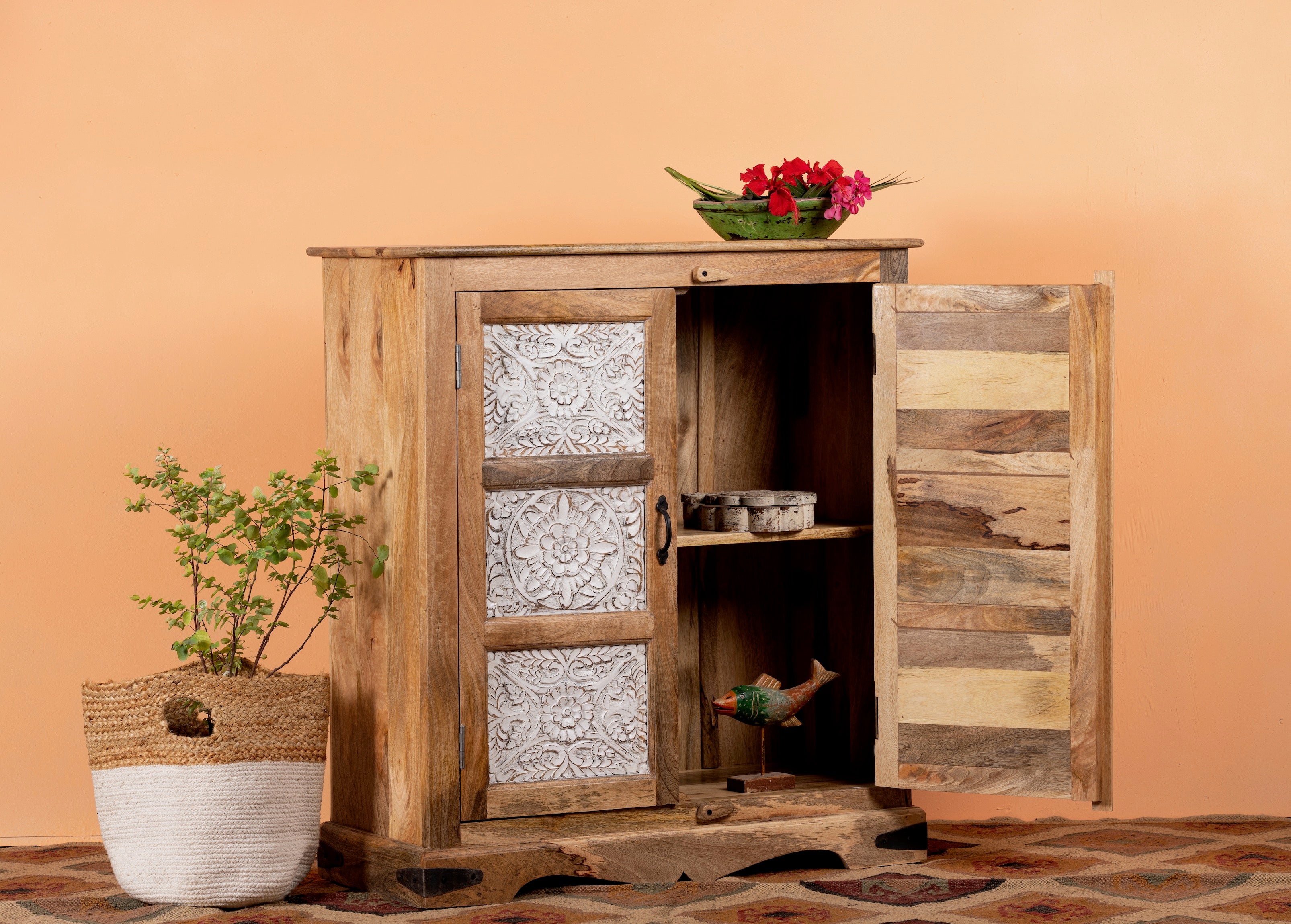 Side angle image with open doors f a carved sideboard / bedroom furniture in mango wood with white-washed floral engravings, 90 × 40 × 100 cm.