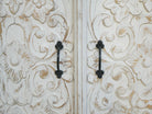 Close up image of a white washed wooden cabinet made from mango wood with hand-carved Indian floral patterns, rustic Mediterranean-style furniture, 90 × 97 × 40 cm.