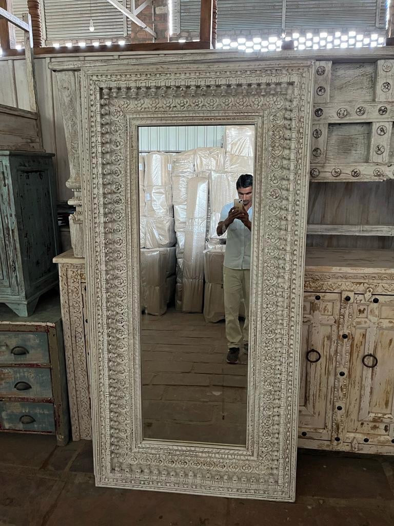 Warehouse pic of a tall white washed wall mirror with hand carved wooden mango wood frame; 180 × 90 × 10 cm.