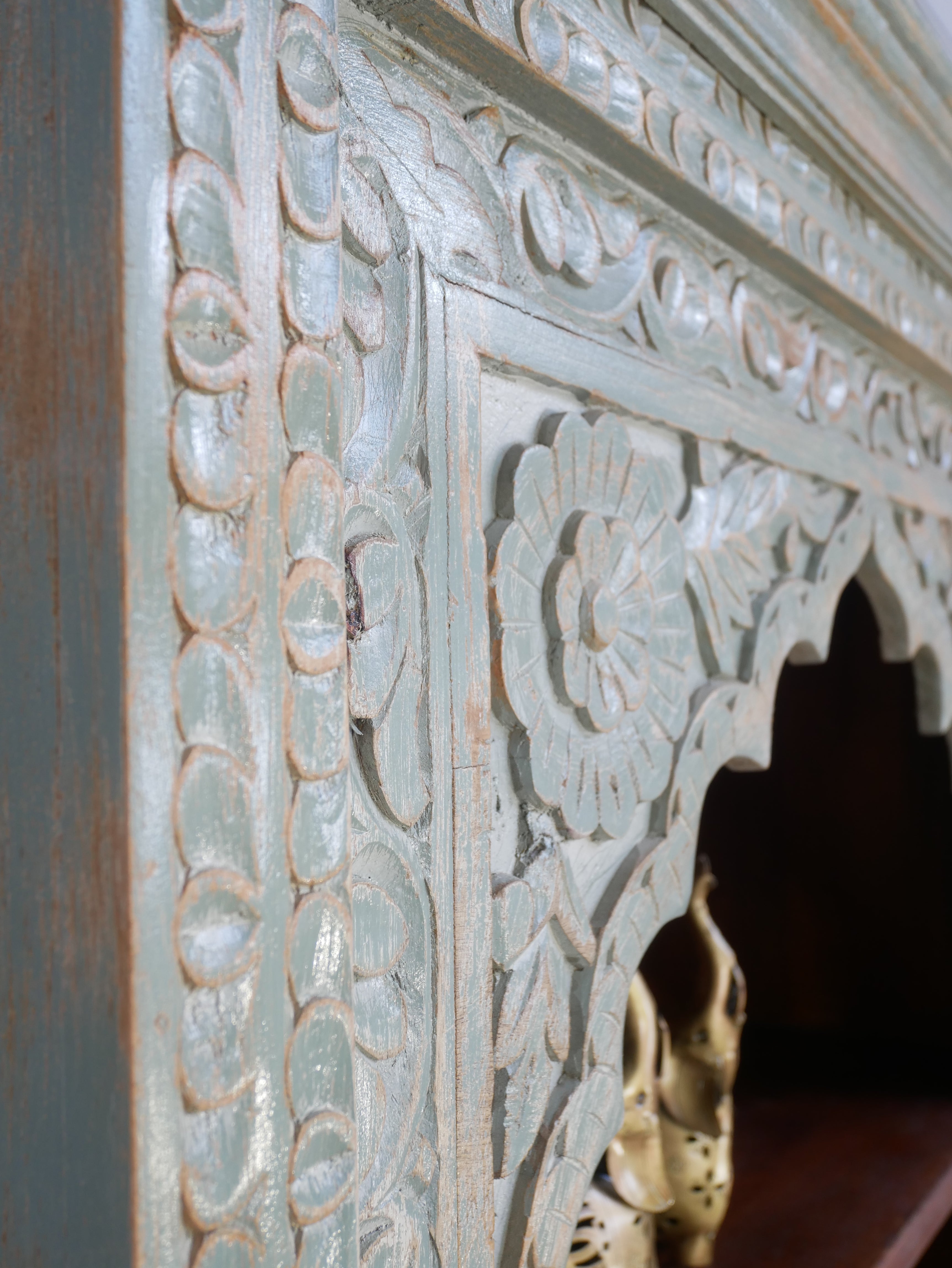 Close up image of a hand-carved mango wood bookcase with Mediterranean design and open shelving – mango wood shelving and hand carved wooden furniture with natural finish.