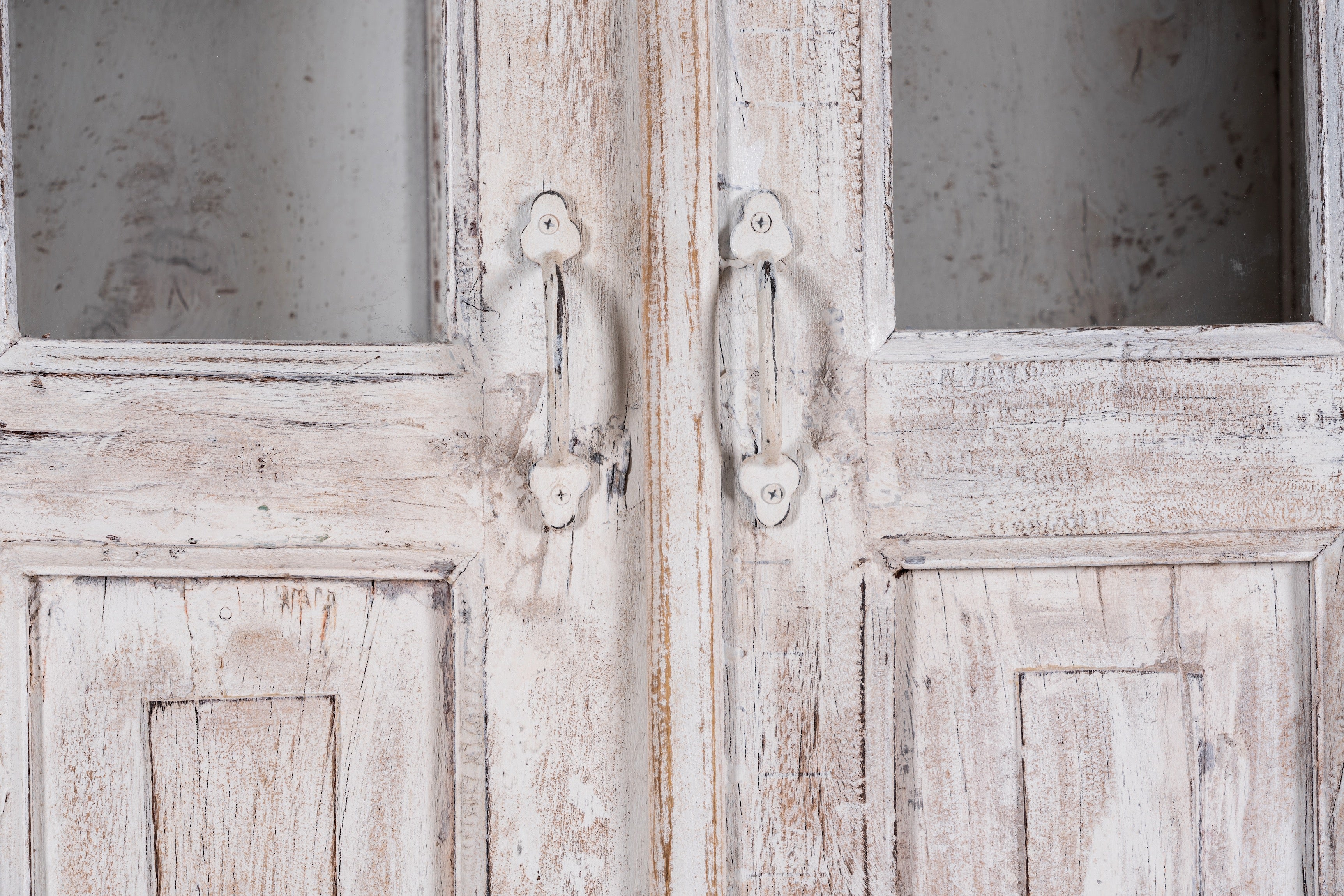 Close up image of a refurbished antique teak wood display cabinet with whitewashed finish and glass doors – wooden display cabinet blending Mediterranean charm and timeless craftsmanship.