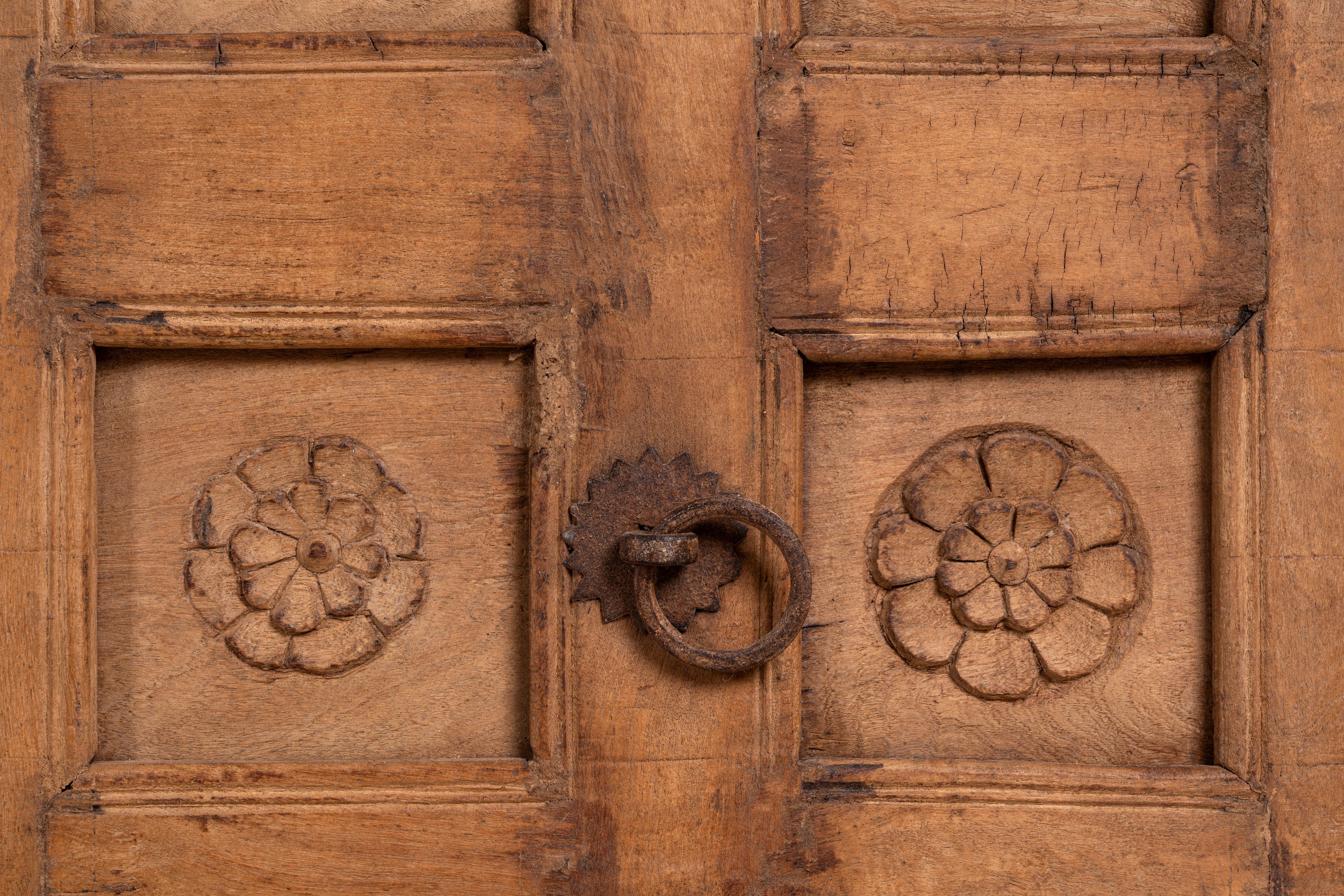 Close up image of a Okha antique Indian teak door repurposed as a decorative wall panel or old door headboard, featuring original hand-carved detailing and a naturally aged finish—an authentic piece of old Indian door furniture.