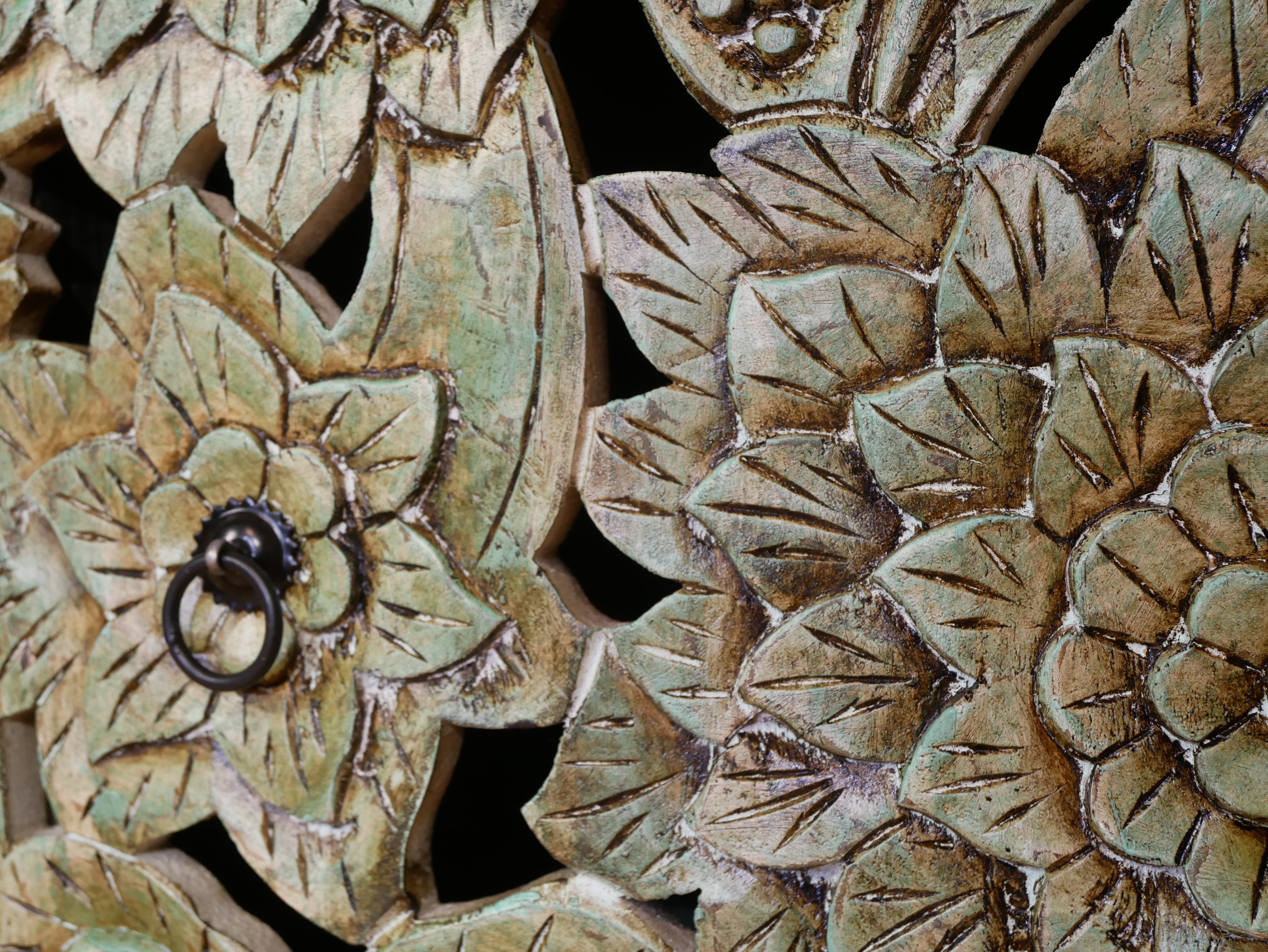 Close up image of a carved mango wood lowboard with green floral doors, black frame, and open shelving, 150 × 60 × 40 cm.