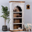 Side angle image of a hand-carved mango wood bookshelf with arched frame and whitewashed finish – carved wooden furniture and mango wood shelving with Indian-inspired design.