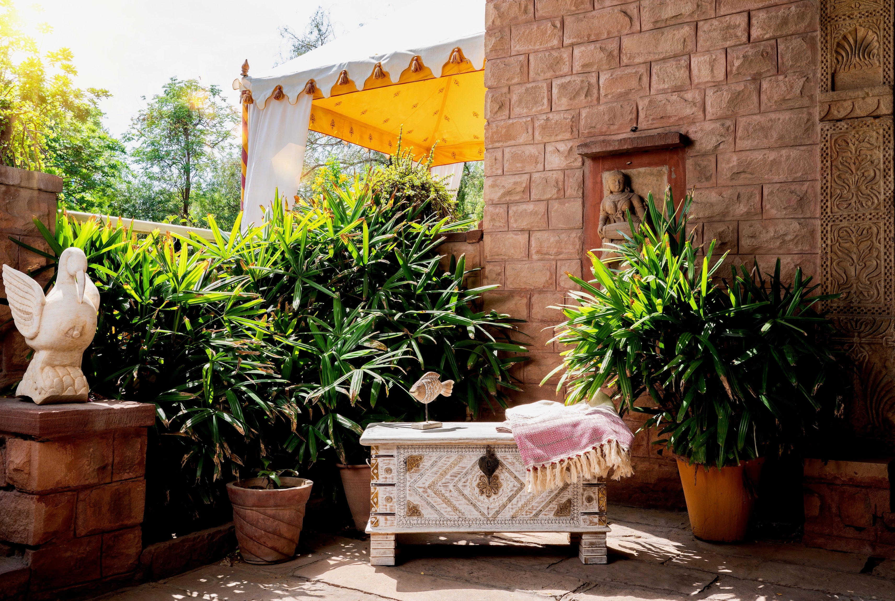 Lifestyle image of a handcrafted mango wood chest with brass inlays and carvings – wood chest box for boho style interiors, perfect as coffee table or bedroom storage.