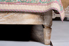 Close up image of a leg of a handcrafted Indian bed Tapti in solid mango wood with rattan panels, artisanal bedroom furniture, 180 × 200 cm.